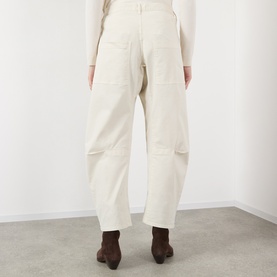 Model wearing Nili Lotan stone wide-leg trousers, rear view, styled with a cream knit top and dark brown ankle boots.