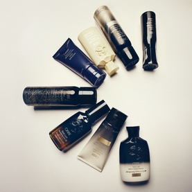 Oribe Gold Lust Dry Heat Protection Spray shown alongside a collection of Oribe haircare products arranged on a white surface.