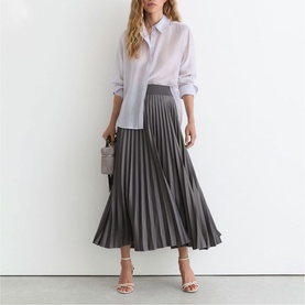 Model wearing Reiss grey pleated midi skirt with white shirt, styled with strappy heels and a small grey bag