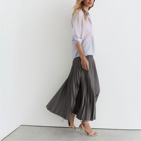 Model wearing Reiss grey pleated maxi skirt with white sheer blouse and silver strappy heeled sandals