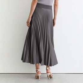 Model wearing Reiss grey pleated midi skirt with wide waistband, styled with white strappy heeled sandals