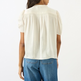 Model wearing Paige Antique White top, back view, short puff sleeves and gather detailing, styled with blue wide-leg jeans