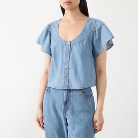 Model wearing Paige top in Palos Verdes blue denim, flutter sleeves, scoop neck, button-front cropped fit, styled with denim jeans