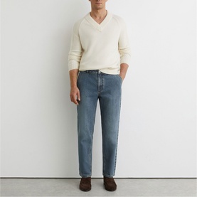 Model wearing Reiss vintage blue wash jeans in a relaxed straight fit, styled with a cream V-neck knit and brown suede loafers