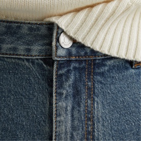 Reiss vintage blue wash jeans close-up showing silver button waistband detail, styled with a cream ribbed knit jumper