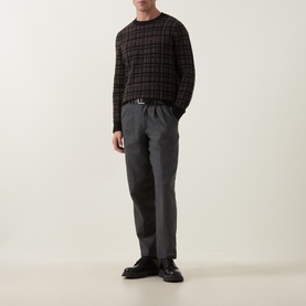 Model wearing Tiger of Sweden Dusty Brown Melange merino wool crew neck jumper with dark check pattern, styled with grey trousers and black loafers.