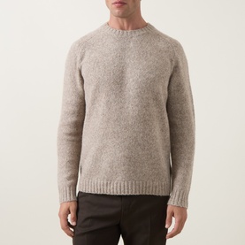 Model wearing Tiger of Sweden stone crew neck knit jumper in yak, alpaca and wool blend, styled with dark brown trousers