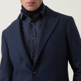 Model wearing Tiger of Sweden Easer Single-Breasted Suit Jacket in Sea, styled with a dark turtleneck, button fastenings and lapel collar visible.