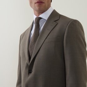 Model wearing Tiger Sweden stone suit jacket in yak, alpaca and wool blend, styled with white shirt and brown tie