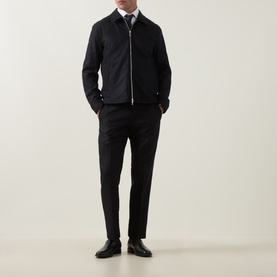 Model wearing Tiger of Sweden Blue Function suit trousers with matching zip jacket, white shirt, tie and black leather shoes.