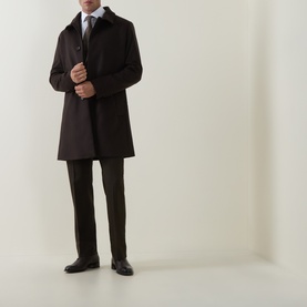 Model wearing Tiger of Sweden Tenser Slim Suit Trousers in Coffee, paired with a dark overcoat, tie, and black dress shoes.