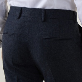 Model wearing Tiger of Sweden Midnight Blue wool suit trousers, rear view showing belt loops and welt pockets, styled with white shirt.