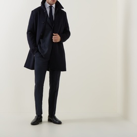 Model wearing Tiger Sweden Midnight Blue wool-blend suit trousers, styled with a matching navy overcoat, light blue shirt and black Oxford shoes.