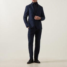 Model wearing Tiger of Sweden sea blue suit trousers with matching blazer, black roll-neck and dark loafers