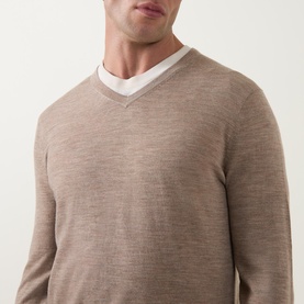 Model wearing Tiger of Sweden Beige Melange wool V-neck jumper, styled over a white crew-neck T-shirt.