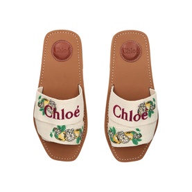 Chlo&eacute; yellow canvas slide sandals with embroidered logo and floral print, tan leather footbed, overhead flat lay view