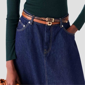 Model wearing Maje dark blue denim midi skirt with tan leather belt featuring gold heart buckle, styled with a dark green ribbed top.