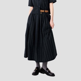 Model wearing Maje Womens French Dress in black with subtle dot pattern, styled with a tan belt and black loafers