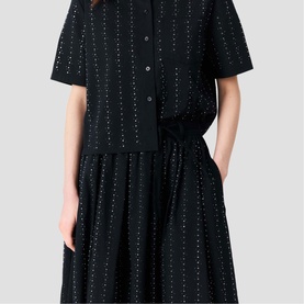 Model wearing Maje Womens French Dress in black with silver metallic dot detail, short sleeves, button front and full pleated skirt