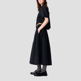 Model wearing Maje Womens French Dress in black broderie fabric, midi length, with matching top and black loafers
