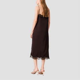 Model wearing dark brown slip midi dress with lace hem trim, styled with strappy gold sandals, back view