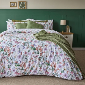 Belledorm Cleo Duvet Set Multi, white with floral print in pink, purple and green, styled on a double bed with green throw and pillows