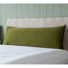 Belledorm Velvet Bolster Cushion in olive green, long rectangular shape with soft velvet texture, styled on a bed with white bedding.