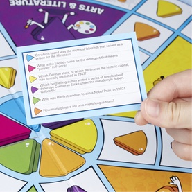 Multicoloured trivia board game close-up showing question card held by hand, with colourful pie-shaped game pieces on board