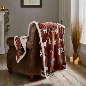Deyongs brick sherpa throw with dog print draped over a brown leather armchair in a cosy living room setting