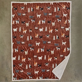 Deyongs brick cat-print throw with cream sherpa reverse, featuring multicoloured cats on a rust-red ground