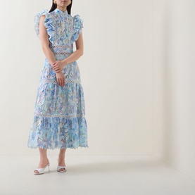 Model wearing Elliatt bluemulti floral midi dress with lace trim inserts, ruffle neckline and cap sleeves, styled with white heeled mules