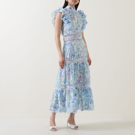 Model wearing Elliatt blue multi floral midi dress with ruffle sleeves, lace trim inserts, and tiered skirt, styled with white heeled mules.