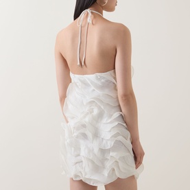 Model wearing Elliatt white halterneck mini dress with tiered ruffle skirt, open back with tie detail, shown from behind