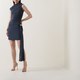 Model wearing Elliatt Marisol Ruched Top & Skirt Set in charcoal, featuring mock neck, asymmetric drape, and side sash, styled with gold strappy