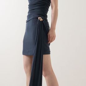 Model wearing Elliatt Marisol Ruched Top & Skirt Set in Charcoal, featuring draped skirt with gold-tone hardware embellishment and asymmetric drape