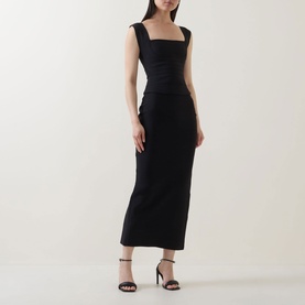 Model wearing Elliatt black midi dress with square neckline, sleeveless fit, ruched sides, paired with black strappy heels