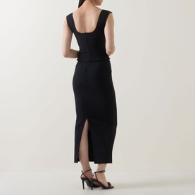 Model wearing Elliatt black midi skirt with back split, styled with matching sleeveless top and black strappy heels