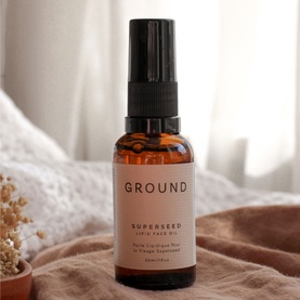 Ground Wellbeing Superseed Lipid Face Oil in amber glass pump bottle, styled on soft fabric with dried botanicals