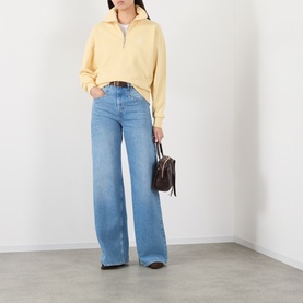 Model wearing Isabel Marant Etoile yellow half-zip cotton sweatshirt, styled with wide-leg blue jeans and brown leather shoulder bag.
