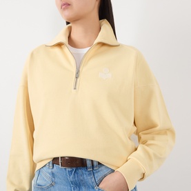 Model wearing Isabel Marant Etoile yellow half-zip sweatshirt with small logo embroidery, styled with blue jeans and a brown belt.
