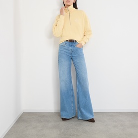 Model wearing Isabel Marant Etoile yellow sweat with half-zip neck, styled with wide-leg light blue jeans and brown boots.