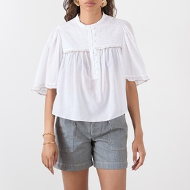 Model wearing Isabel Marant Etoile Douna Embroidered Blouse in white with scalloped detail and ruffled sleeves, styled with grey shorts