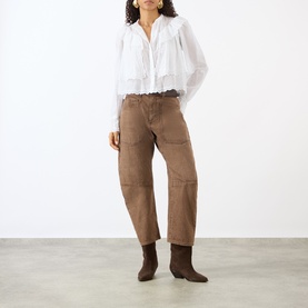 Model wearing Isabel Marant Etoile white cotton blouse with ruffle detail, styled with taupe cargo trousers and brown heeled boots.