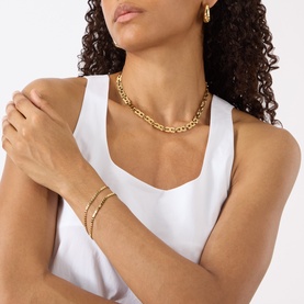Model with Jenny Bird Double Amalfi Bracelet in gold, double-chain polished finish on wrist, styled with matching chain necklace and white vest top