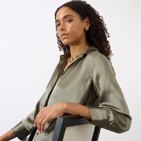 Model with Jenny Bird Heart Button Earrings in gold, heart motif, polished finish, styled with a sage satin shirt