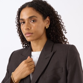 Model with Jenny Bird Monroe Hoop Earrings in gold, four-hoop design with polished finish, styled with dark blazer and gold bracelet.