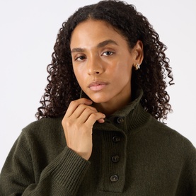 Model with Jenny Bird Florence Mini Hoop Earrings in two-tone gold and silver, worn with a dark olive ribbed knit jumper.