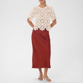 Model wearing Kaffe broken white crochet floral short-sleeve top, styled with rust midi skirt and white flat sandals