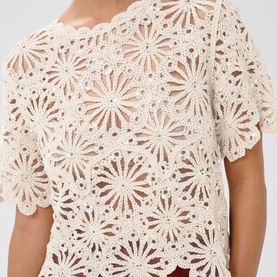 Model wearing Kaffe top in Broken White with silver detail, featuring allover floral crochet lace pattern and short scalloped sleeves
