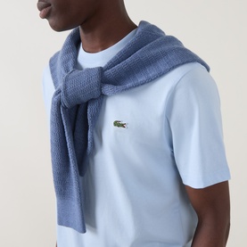 Model wearing Lacoste Croc Logo T-Shirt in Rill blue with embroidered croc chest logo, styled with a matching blue knit scarf.